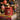 Red personalised Christmas candle tin with a lit flame, showing a nutcracker illustration and the name “Jessica,” placed on two stacked books titled “Joyful Living” and “Color Pop,” with a blurred Christmas tree in the background.